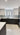 Modern kitchen with sleek black cabinets, white marble floor, and glass backsplash