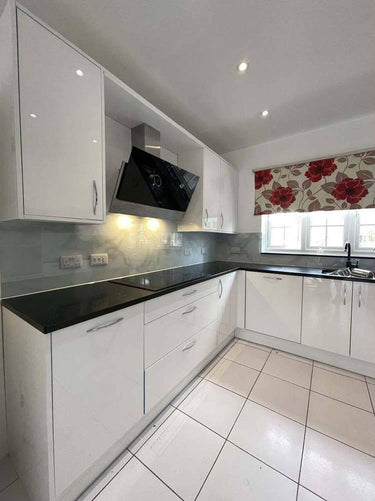 Modern kitchen with white gloss cabinets, black countertop, and glass splashback for luxury residential interiors