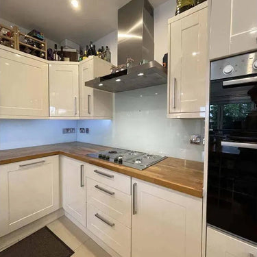 Modern kitchen with white cabinets, wooden countertops, and a sleek glass backsplash