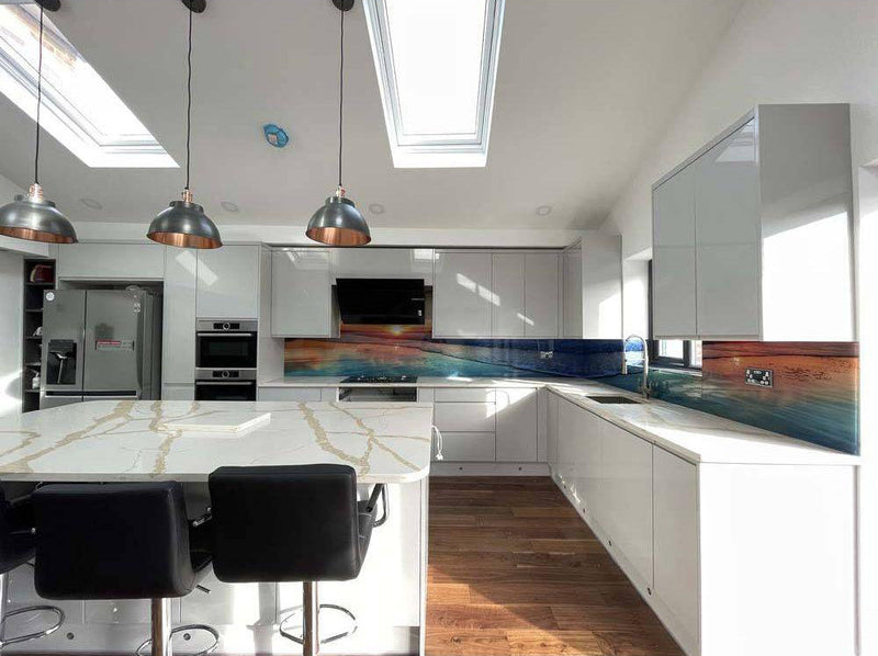 Modern kitchen with bespoke glass splashback featuring ocean sunset design, white cabinets, and skylights
