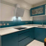 Modern kitchen with teal glass splashback and sleek cabinetry, featuring LED lighting and contemporary design.