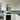 Modern kitchen with sleek white cabinets and a light green glass backsplash, featuring built-in oven and gas hob.