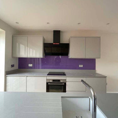 Vibrant purple glass kitchen splashback with modern white cabinets and stainless steel appliances
