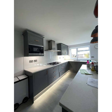 Modern kitchen with sleek grey cabinets, white countertop, and LED under-cabinet lighting