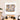 Abstract watercolor wall art with fragmented faces, displayed above a wooden dining table in a modern home.