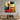 Bespoke abstract geometric glass art panel with bold red, yellow, green, and black shapes mounted above modern wooden console.