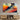 Abstract art print with bold geometric shapes in warm orange, red, and teal, displayed above a modern wooden console in a contemporary living space.