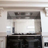 Bespoke decorative glass backsplash with etched pattern above black range cooker in luxury kitchen