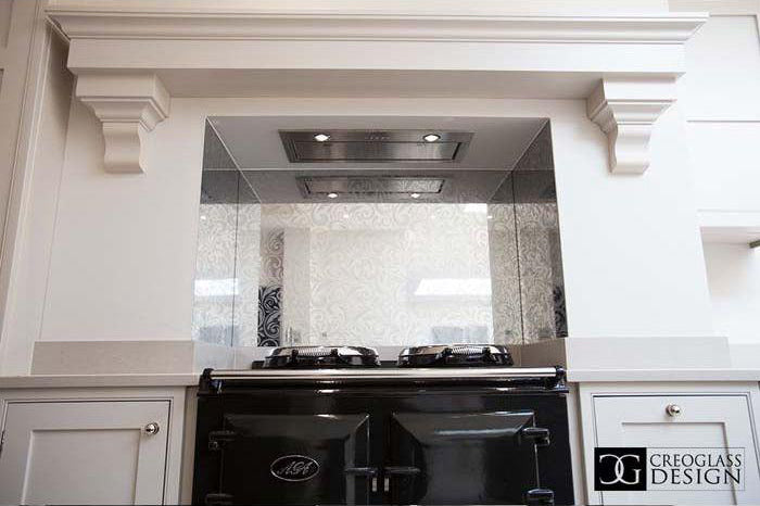 Bespoke decorative glass backsplash with etched pattern above black range cooker in luxury kitchen