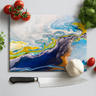 Galaxy-themed glass chopping board with chef knife, tomatoes, garlic, and fresh basil on white surface