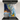 Modern kitchen stovetop with stainless steel pot and colorful abstract backsplash art panel