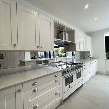 Modern white kitchen with sleek cabinets, stainless steel range, and glass backsplash