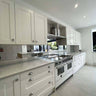 Modern white kitchen with sleek cabinets, stainless steel range, and glass backsplash