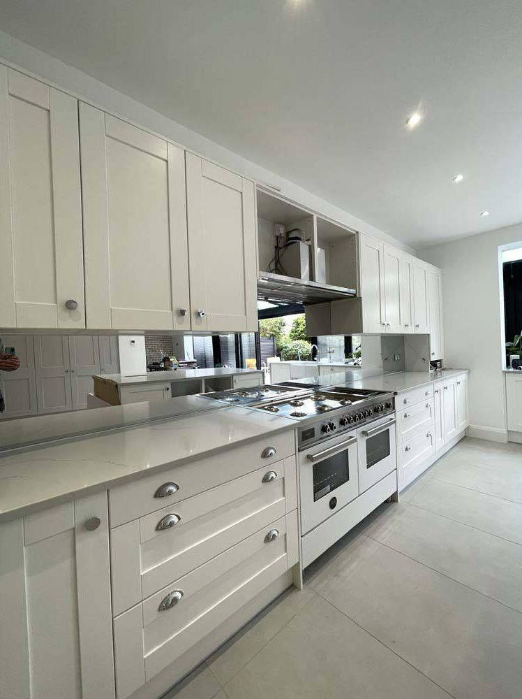 Modern white kitchen with sleek cabinets, stainless steel range, and glass backsplash