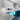Modern kitchen with teal glass cabinets, white countertops, and sleek pendant lighting