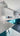 Modern kitchen with teal glass cabinets, white countertops, and sleek pendant lighting