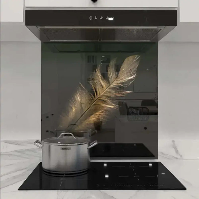 Custom glass kitchen splashback with golden feather design, modern induction cooktop, sleek range hood