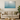 Modern living room with beige sofa, round wooden coffee table, green plant, and gradient teal wall art
