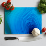Blue agate design glass chopping board with tomatoes, basil, garlic, and chef knife on white surface