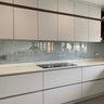 Modern kitchen with frosted glass backsplash and sleek white cabinetry