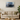 Modern beige sofa with green and beige pillows in living room featuring abstract wall art and round wooden coffee table