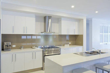 Modern kitchen with sleek white cabinets, stainless steel range hood, and glass backsplash
