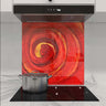 Vibrant red and gold swirl decorative glass splashback in modern kitchen with induction hob