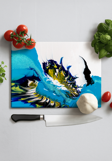 Colorful resin cutting board with blue and yellow design surrounded by cherry tomatoes, garlic, basil, and kitchen knife