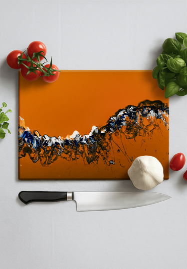 Orange cutting board with abstract black, white, and blue design, surrounded by cherry tomatoes, garlic, basil, and a chef's knife