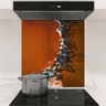 Modern kitchen stovetop with stainless steel pot and abstract orange-black glass backsplash panel