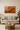 Modern living room with beige sofa, round wooden coffee table, and abstract orange and black wall art