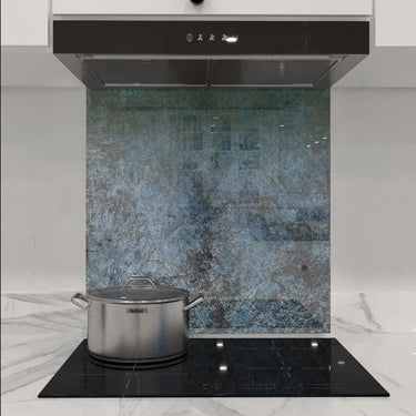 Textured blue-green decorative glass kitchen splashback behind induction hob and extractor hood
