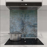 Textured blue-green decorative glass kitchen splashback behind induction hob and extractor hood