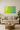 Modern living room with beige sofa, round wooden coffee table, and abstract green and yellow wall art