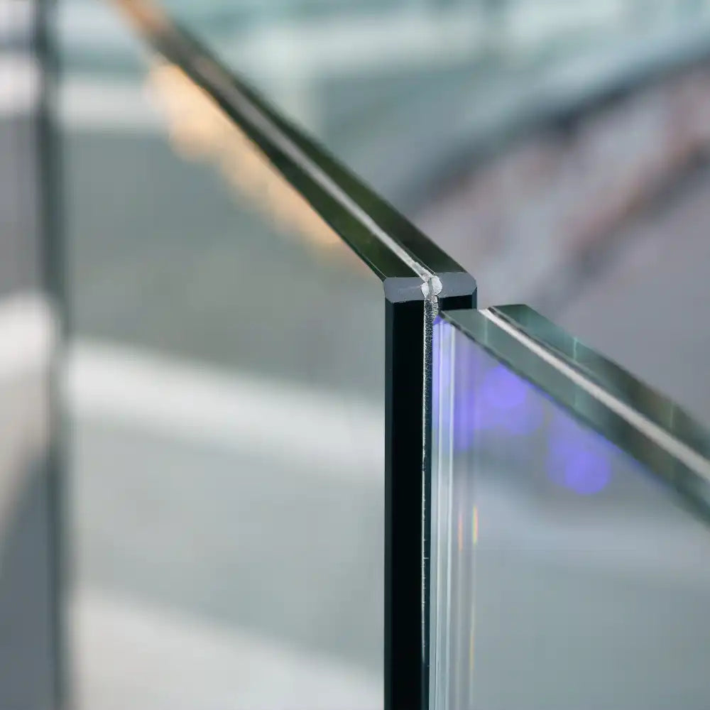 Close-up of sleek glass balustrade with black frame and purple LED backlighting, ideal for modern interiors.