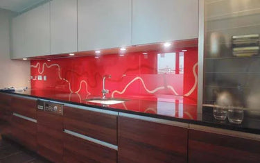 Vibrant red glass splashback with white wave design in modern kitchen, sleek cabinets and underlighting