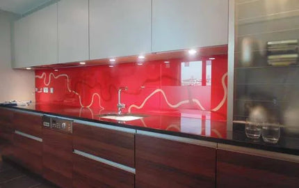Red decorative glass backsplash with white wave design in modern kitchen, featuring sleek cabinets and LED lighting.