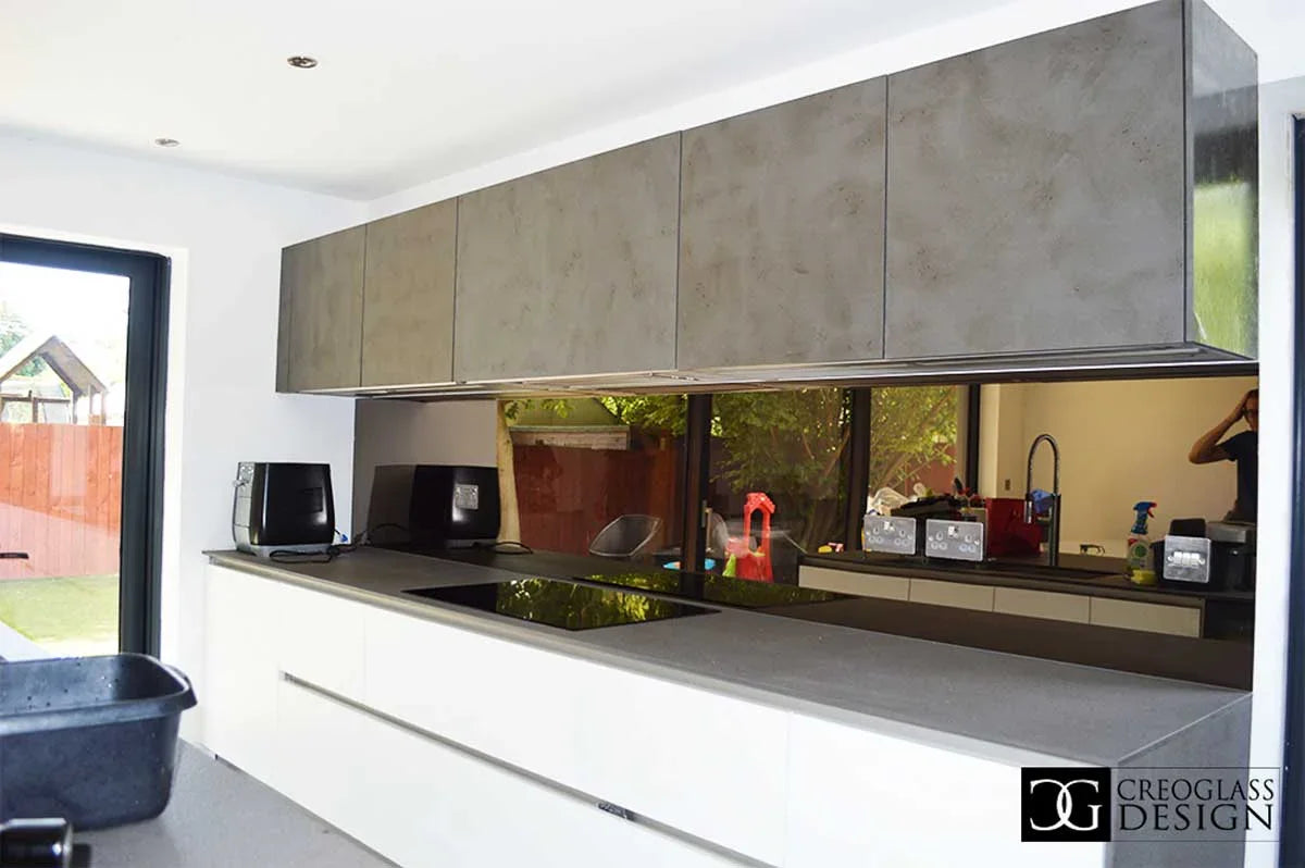 Modern kitchen with sleek concrete-style glass splashback and minimalist white cabinetry