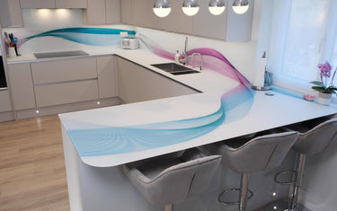 Modern kitchen with bespoke glass splashback featuring blue and pink wave design, sleek white countertops, and bar stools.