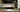 Luxury kitchen with bespoke decorative glass backsplash and golden bonsai art, featuring elegant black cabinetry and marble countertops.