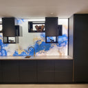 Bespoke blue and gold marbled glass backsplash in modern kitchen with LED lighting