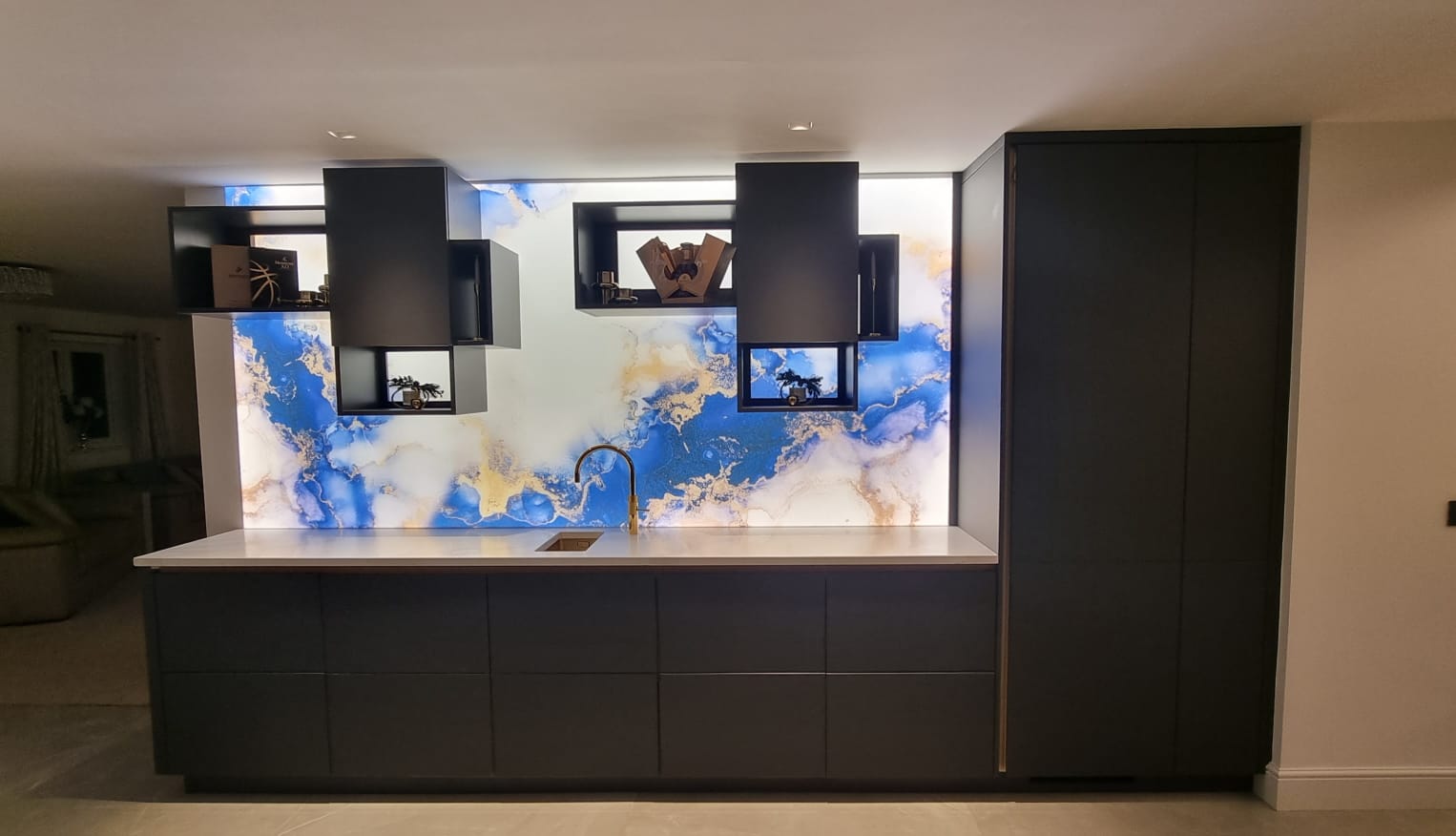 Bespoke blue and gold marbled glass backsplash in modern kitchen with LED lighting