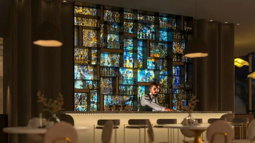 Bespoke decorative glass wall with LED backlighting in luxury bar setting, featuring stained-glass panels and modern bar design