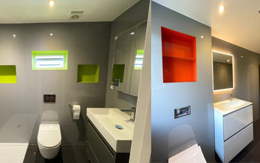 Modern bathroom with grey glass splashback, vibrant green & orange recessed shelves, and sleek white vanity