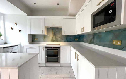 Modern kitchen with bespoke glass splashback featuring marble effect design, white cabinetry and integrated appliances