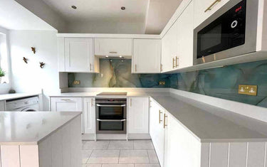 Modern kitchen with bespoke glass splashback in teal marble design, white cabinets, and stainless steel appliances