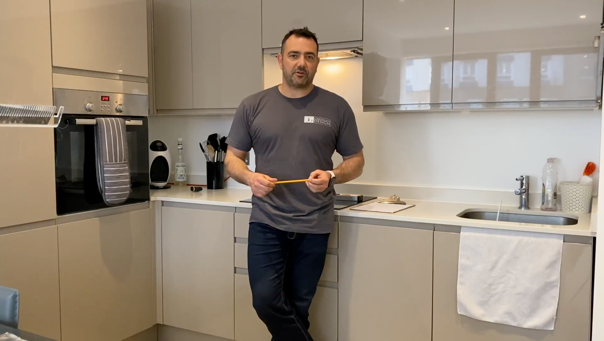 Man in modern kitchen with sleek glass cabinets and contemporary design features