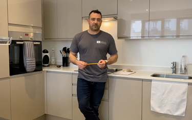 Man in modern kitchen with sleek glass cabinets and contemporary design features