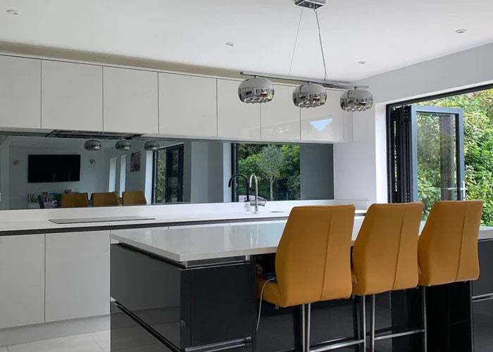Modern kitchen with sleek white cabinets, black island, and large feature mirror above countertop