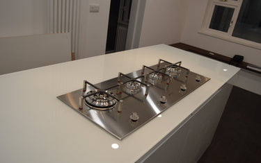 Modern kitchen with sleek white glass countertop and stainless steel gas hob